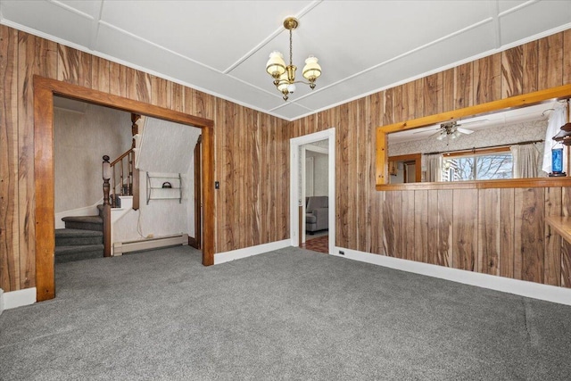 carpeted spare room featuring stairs, wood walls, a baseboard radiator, and a notable chandelier