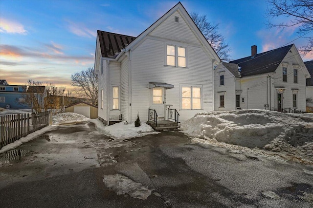 view of front of house featuring a garage, fence, driveway, and an outdoor structure