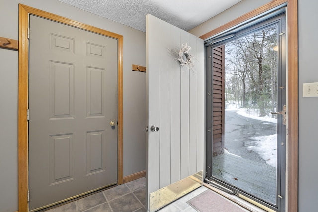 doorway with tile patterned flooring and a textured ceiling