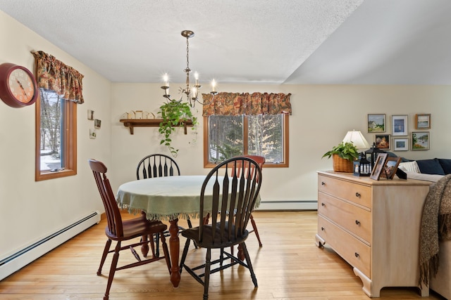 dining room with a baseboard heating unit, a chandelier, a textured ceiling, and light wood finished floors