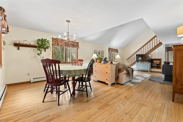 dining room with lofted ceiling, stairway, baseboard heating, light wood-style floors, and a chandelier