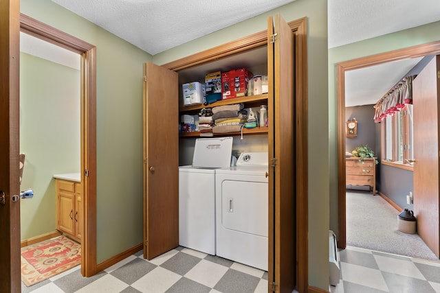 laundry area with a textured ceiling, laundry area, baseboards, light floors, and washing machine and clothes dryer