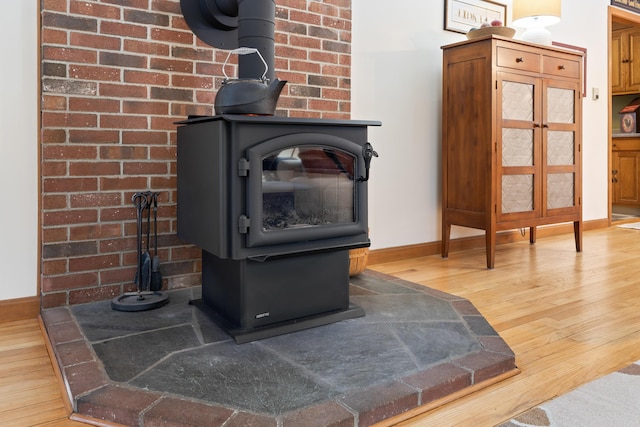 interior details with a wood stove, baseboards, and wood finished floors