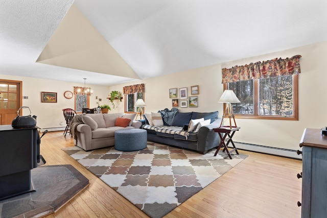 living room featuring lofted ceiling, hardwood / wood-style floors, a baseboard radiator, and an inviting chandelier