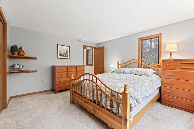 bedroom featuring light carpet, a textured ceiling, and baseboards