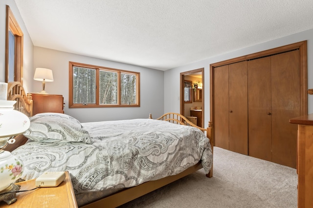 carpeted bedroom featuring a closet, a textured ceiling, and ensuite bath