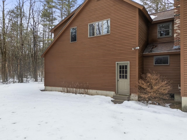 view of snow covered exterior with roof with shingles