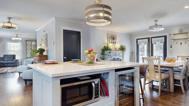 7 Dogleg Dr, Windham, ME 04062 - kitchen featuring wine cooler, stainless steel microwave, light countertops, ornamental molding, and dark wood-style flooring