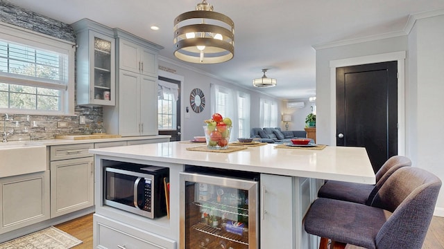 7 Dogleg Dr, Windham, ME 04062 - kitchen featuring wine cooler, stainless steel microwave, crown molding, gray cabinets, and plenty of natural light