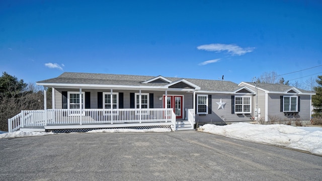 ranch-style home featuring covered porch and a shingled roof