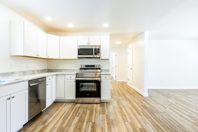 kitchen featuring white cabinetry, light wood-style flooring, appliances with stainless steel finishes, and baseboards