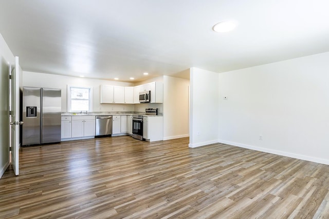 kitchen with appliances with stainless steel finishes, light countertops, a sink, and wood finished floors