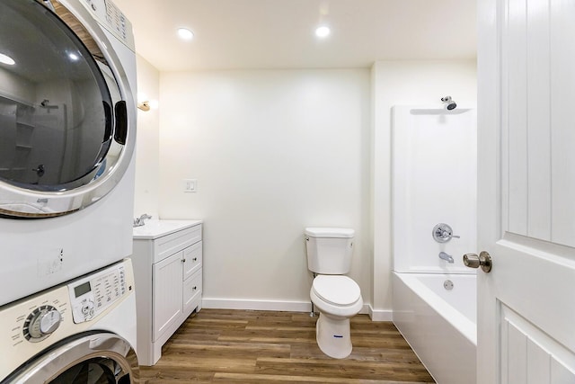 full bathroom featuring stacked washer and dryer, baseboards, toilet, wood finished floors, and vanity