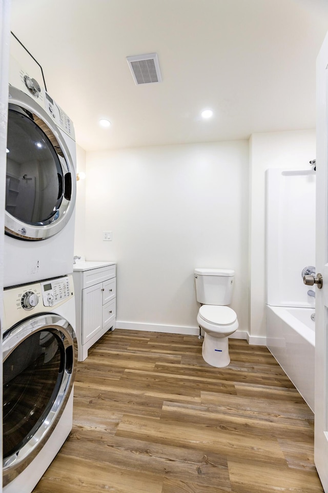 washroom featuring visible vents, light wood-style flooring, stacked washing maching and dryer, laundry area, and baseboards