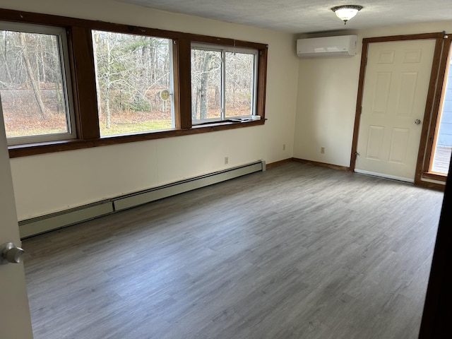 35 Bath Rd, Brunswick, ME 04011 - unfurnished room with baseboard heating, a wall unit AC, wood finished floors, and baseboards