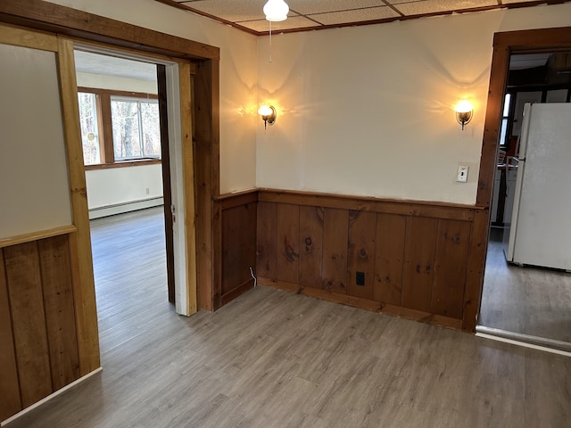 35 Bath Rd, Brunswick, ME 04011 - empty room with wood walls, a baseboard radiator, light wood-type flooring, and a wainscoted wall