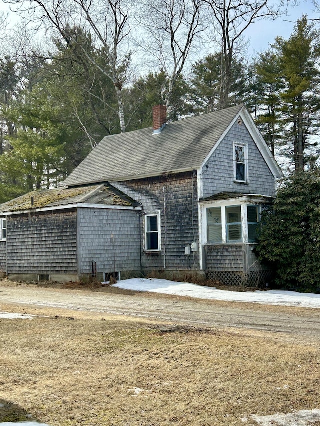 view of property exterior featuring a chimney and a shingled roof