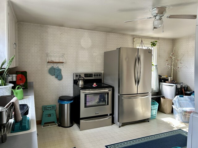 kitchen with wallpapered walls, ceiling fan, light floors, and stainless steel appliances