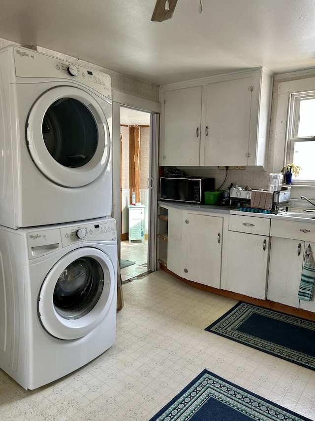 laundry room featuring a ceiling fan, light floors, laundry area, a sink, and stacked washer / drying machine