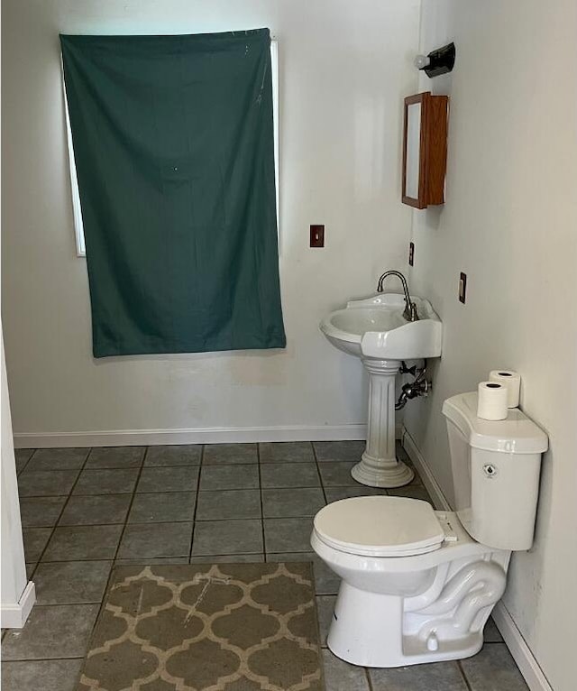 bathroom with toilet, baseboards, a sink, and tile patterned floors