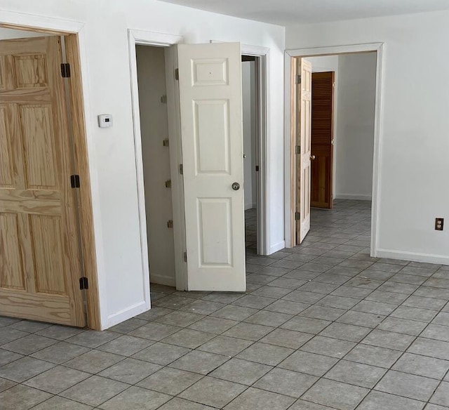 unfurnished room with light tile patterned floors and baseboards