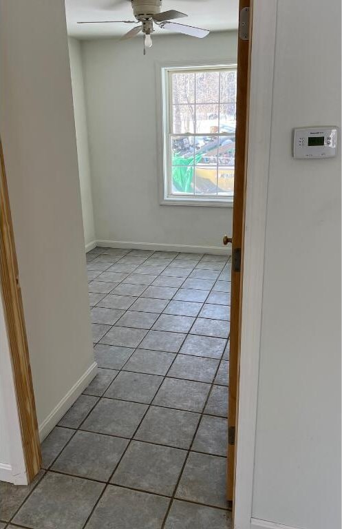 unfurnished room featuring ceiling fan, baseboards, and light tile patterned flooring