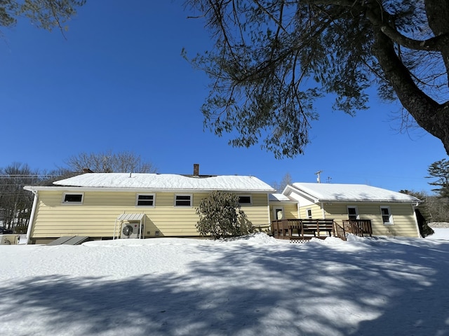 snow covered property with a chimney and a wooden deck