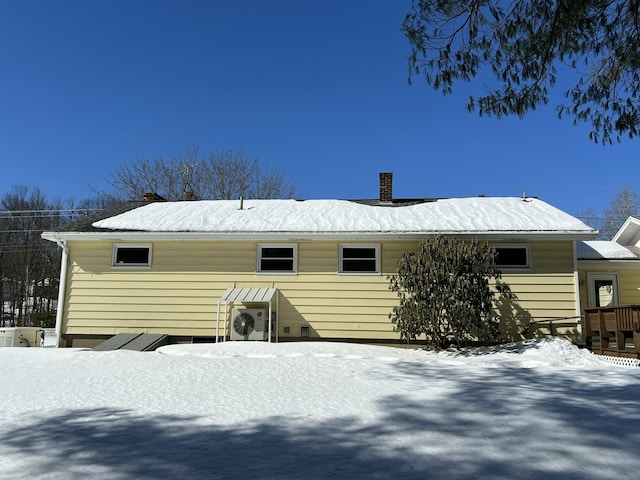 snow covered rear of property with a chimney