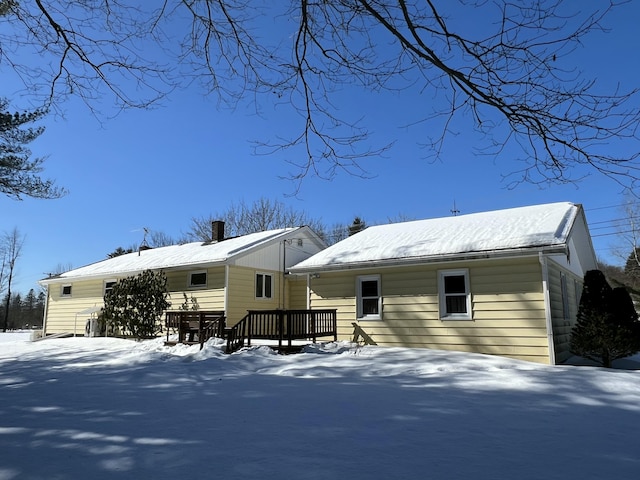 snow covered rear of property featuring a chimney