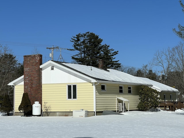 snow covered rear of property featuring a chimney