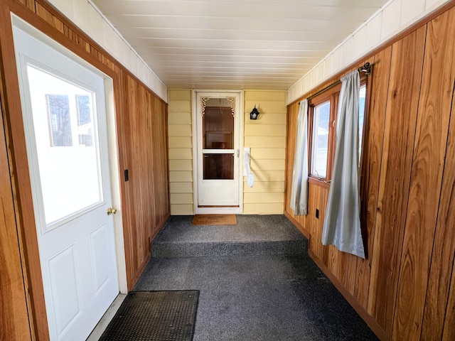 interior space with wooden walls and dark colored carpet