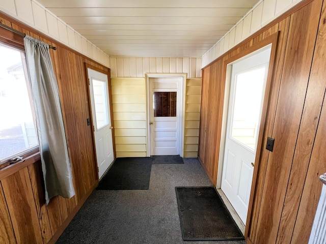 doorway to outside with a wealth of natural light and dark carpet