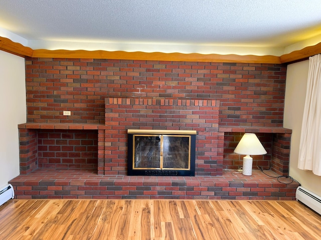 unfurnished living room featuring a baseboard heating unit, a textured ceiling, and wood finished floors