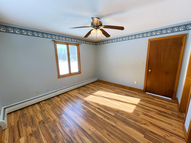 unfurnished room with a textured ceiling, a baseboard radiator, wood finished floors, a ceiling fan, and baseboards