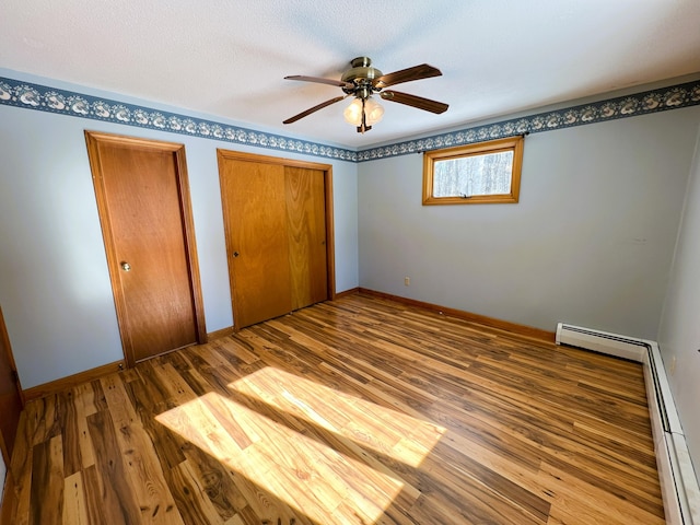 unfurnished bedroom featuring multiple closets, a textured ceiling, baseboards, and wood finished floors