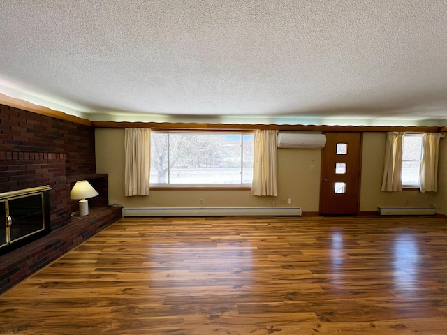 unfurnished living room with wood finished floors, baseboard heating, a healthy amount of sunlight, a fireplace, and a wall mounted AC