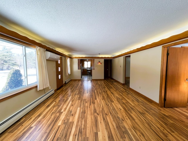 unfurnished living room with a textured ceiling, wood finished floors, a baseboard radiator, and a wall unit AC