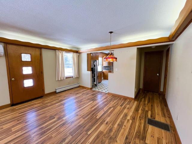 interior space with baseboards, visible vents, wood finished floors, baseboard heating, and a textured ceiling