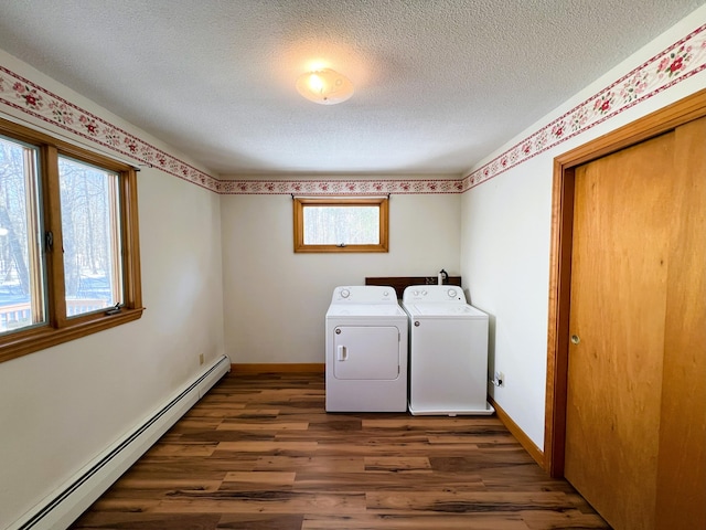 clothes washing area featuring laundry area, baseboards, wood finished floors, a baseboard heating unit, and separate washer and dryer