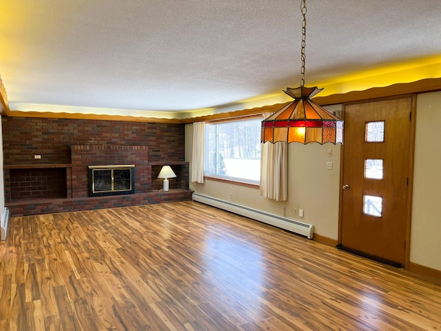 unfurnished living room with baseboards, wood finished floors, a textured ceiling, a fireplace, and a baseboard heating unit