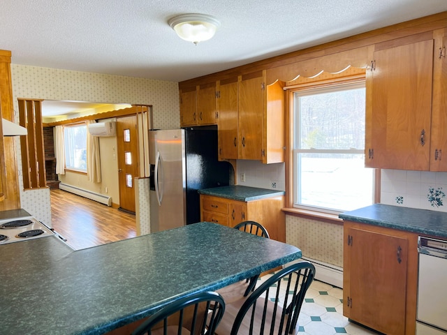 kitchen featuring wallpapered walls, dark countertops, an AC wall unit, light floors, and a baseboard heating unit