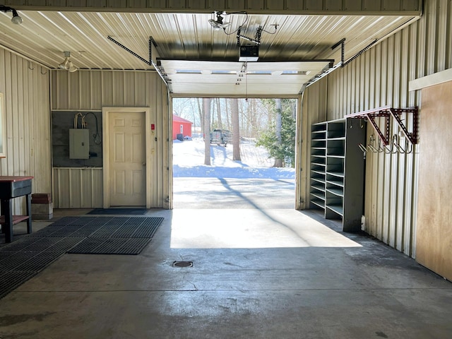 garage with a garage door opener, electric panel, and metal wall