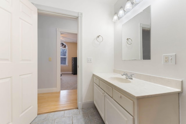 bathroom with a baseboard heating unit, tile patterned flooring, baseboards, and vanity