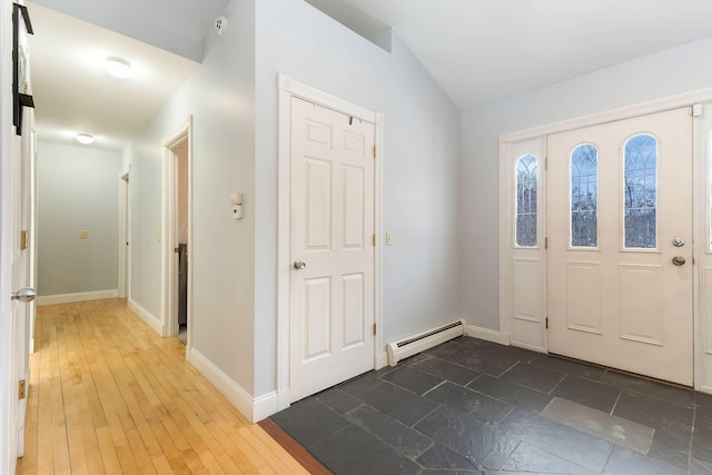 foyer with vaulted ceiling, baseboard heating, wood finished floors, and baseboards