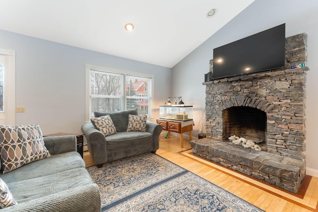 living room featuring vaulted ceiling, a fireplace, and wood finished floors