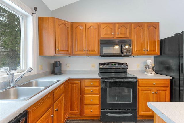 kitchen featuring a sink, vaulted ceiling, light countertops, black appliances, and brown cabinetry