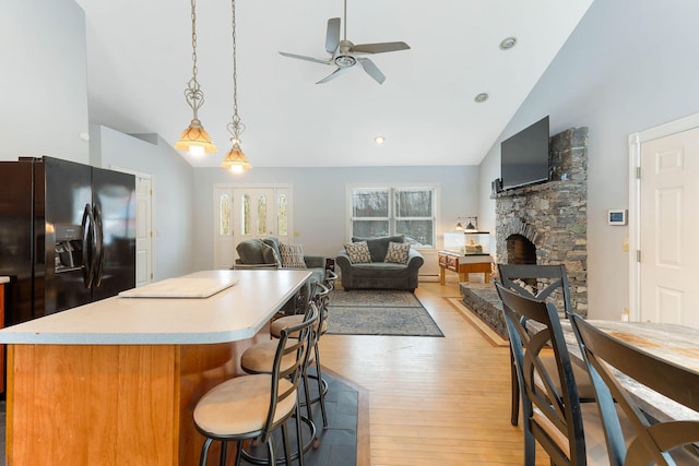 kitchen featuring light wood finished floors, open floor plan, black fridge, and light countertops