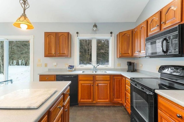 kitchen featuring brown cabinets, light countertops, black appliances, pendant lighting, and a sink