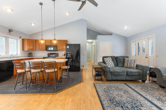 kitchen featuring hardwood / wood-style flooring, a kitchen island, open floor plan, light countertops, and black appliances