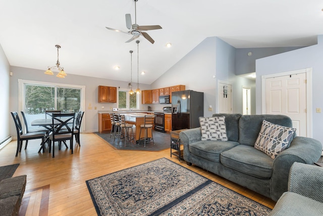 living room with high vaulted ceiling, ceiling fan, light wood-style flooring, and baseboards